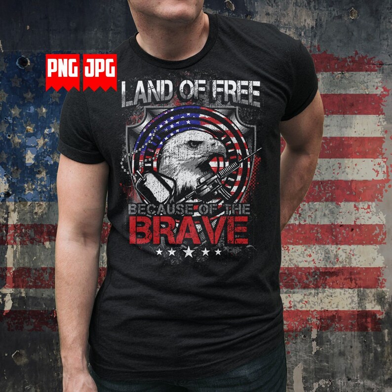 May include: A black t-shirt with a graphic design featuring an eagle holding a rifle, a red, white, and blue American flag, and the text "Land of the Free Because of the Brave".