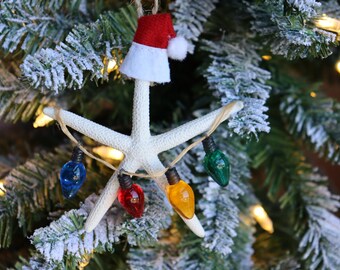 May include: A white starfish Christmas ornament with a red Santa hat and a string of colorful lights. The lights are red, yellow, green, and blue.