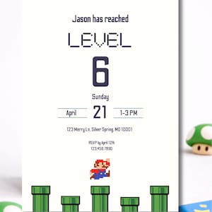K&ouml;nnte beinhalten: Eine wei&szlig;e Einladungskarte mit dem Text "Jason has reached LEVEL 6" in einer pixeligen Schriftart. Die Karte enth&auml;lt Datum, Uhrzeit und Ort sowie ein pixeliges Bild einer Figur, die &uuml;ber gr&uuml;ne Rohre springt.