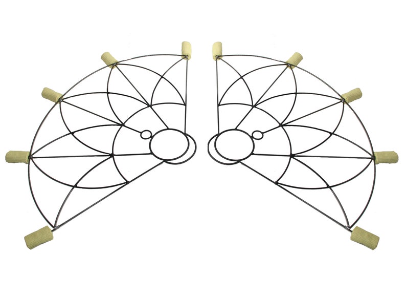 May include: A pair of black metal fire fans, each with a semi-circular frame and a geometric pattern. The fans have circular handles and beige wicks at the ends, designed for fire performance. The fans are symmetrical.
