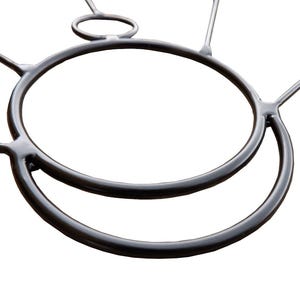 May include: A close-up of a black metal object with a circular design. The object has two large, connected circular shapes, with smaller connecting pieces extending outwards. The background is plain white.