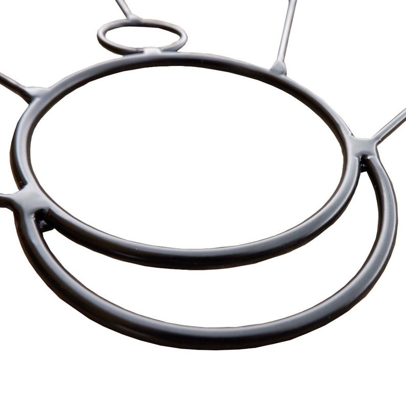 May include: A close-up of a black metal object with a circular design. The object has two large, connected circular shapes, with smaller connecting pieces extending outwards. The background is plain white.