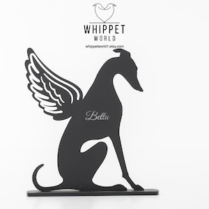Op de afbeelding: Zwart metalen silhouet van een whippet-hond met engelen vleugels, de naam "Bella" is op het lichaam van de hond gegraveerd. Het Whippet World-logo en de Etsy shop URL staan bovenaan.