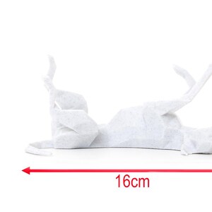 K&ouml;nnte beinhalten: Eine wei&szlig;e Origami-Katze, die auf dem R&uuml;cken liegt, mit den Pfoten in der Luft. Die Papierkatze ist 16 cm lang und 7,5 cm hoch. Die Katze hat ein dezentes Muster aus kleinen grauen Punkten. Der Hintergrund ist wei&szlig;.