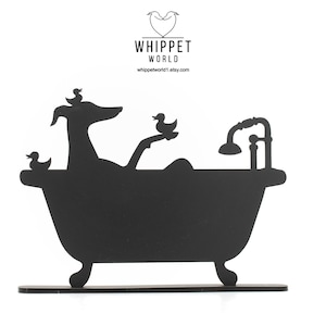 Könnte beinhalten: Schwarze Silhouette eines Whippets, der in einer Badewanne mit Duschkopf und Gummienenten badet. Die Silhouette befindet sich auf einem schwarzen Sockel mit dem Text "Whippet World" und der Website-Adresse "whippetworld1.etsy.com".