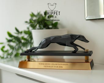 Op de afbeelding: Zwarte geometrische whippet-hondentrofee met een gouden voet. De trofee is voor de Yorkshire Championships Veteran YCH 2026. Het Whippet World-logo staat bovenaan.