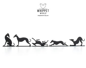 Pode incluir: Silhuetas pretas de cães Whippet em metal em várias poses, incluindo sentado, em pé e correndo. As silhuetas estão dispostas em uma fileira, com o logotipo Whippet World no topo. O fundo é branco.