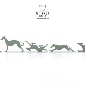 May include: A series of five grey metal whippet dog silhouettes in various poses, from sitting to running. The Etsy shop logo, "WHIPPET WORLD," is at the top, with the shop's website address below. The dogs are on a white background.