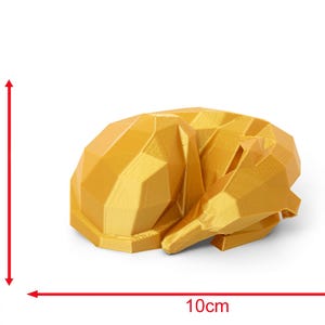 K&ouml;nnte beinhalten: Eine geometrische, goldgelbe Skulptur eines schlafenden Hundes. Die Hundefigur ist etwa 10 cm lang und 5 cm hoch. Das Design weist scharfe Winkel und Facetten auf, was ihm eine moderne, minimalistische &Auml;sthetik verleiht. Der Hund ist zusammengerollt und wirkt friedlich.