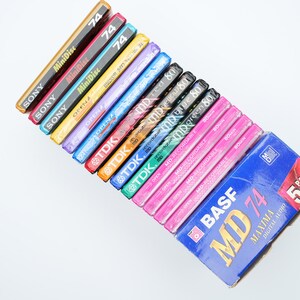 May include: A stack of various brand mini disc audio recording media, including Sony, TDK, and BASF. The top disc is a blue and white BASF MD 74 Maxima Digital Audio 5 pack.