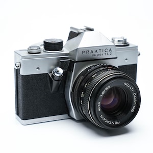 Op de afbeelding: Een zilveren Praktica super TL2 camera met een zwarte Pentacon 1.8/50 lens. De lens heeft een multi-coating label.