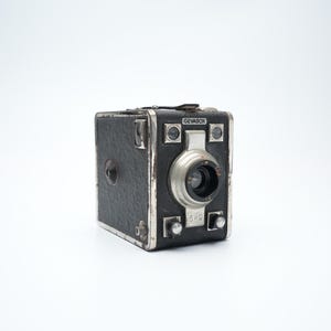 May include: A black and silver vintage camera with the text "GW69" on the front.