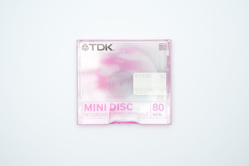 May include: A pink and white TDK Mini Disc with the text "MINI DISC 80 RECORDABLE/ENREGISTRABLE MIN" on the front.