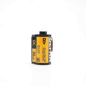 May include: A black and yellow 35mm film canister for color prints. The canister has the text "GETRA DIN 35mm FILM FOR COLOR PRINTS PROCESS C-41 GC 36 EXP. 8" printed on it.
