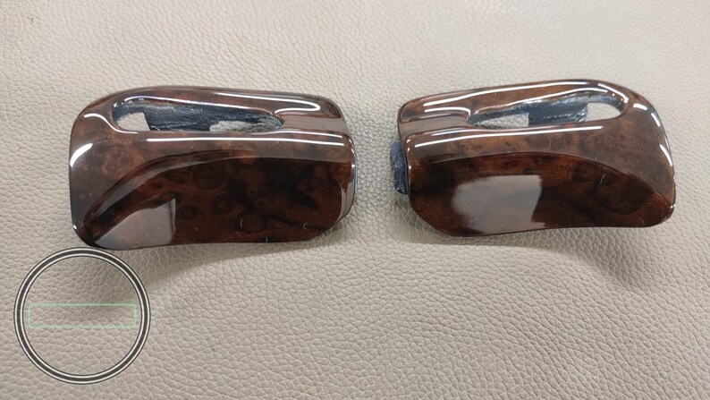 May include: Two brown woodgrain car interior trim pieces with a glossy finish.
