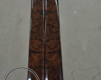 May include: Two glossy, dark brown woodgrain panels with a polished finish. The panels have a unique burl pattern and are vertically oriented. The image includes a circular logo with text that reads "WORLD ELITE CARBON WORKS".
