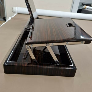 May include: A dark wood tray with a hinged top that folds up and down. The tray has a black finish and a silver metal hinge.