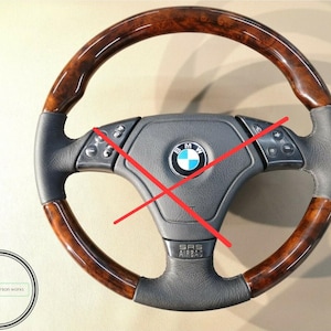 May include: A BMW steering wheel featuring a dark brown burl wood rim and black leather grips. The center hub displays the BMW logo, integrated control buttons on the horizontal spokes, and an SRS AIRBAG label at the bottom center.
