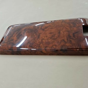 May include: A brown woodgrain-patterned rectangular panel with a glossy finish. The panel has a cutout on the right side.