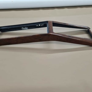 Könnte beinhalten: Ein dunkelbrauner Holzrahmen mit schwarzem Rand. Der Rahmen ist rechteckig mit einer leichten Biegung oben und unten.