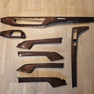 Peut inclure: Ensemble de six pièces de garniture d'intérieur de voiture en bois grainé. Les pièces sont de formes et de tailles variées, et elles sont toutes en bois brun foncé.