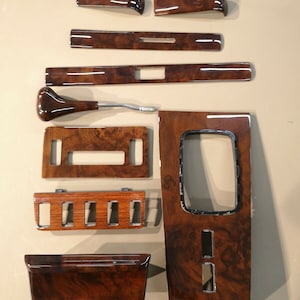 Puede incluir: Un conjunto de 10 piezas de moldura interior de coche de imitación de madera. Las piezas son de varias formas y tamaños, y tienen un acabado marrón oscuro.