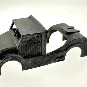 Pode incluir: Um chassi de caminh&atilde;o modelo de pl&aacute;stico preto com uma cabine e uma plataforma. O modelo est&aacute; inacabado e tem uma superf&iacute;cie texturizada.