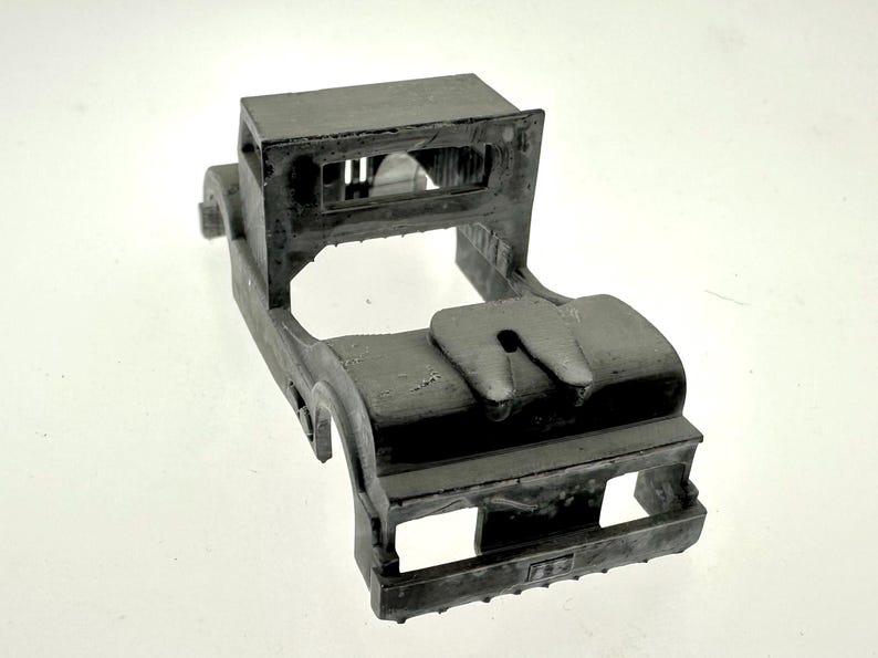 Pode incluir: Um chassi de caminh&atilde;o modelo de pl&aacute;stico cinza com uma cabine detalhada e um engate. O modelo n&atilde;o tem rodas nem carroceria.