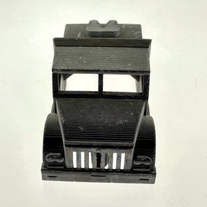 Pode incluir: Um modelo de caminh&atilde;o de brinquedo de pl&aacute;stico preto com uma grelha frontal e far&oacute;is detalhados. O caminh&atilde;o tem uma plataforma e &eacute; feito com uma impressora 3D.