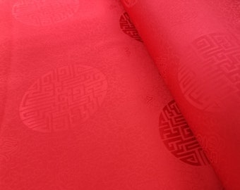 Könnte beinhalten: Roter Stoff mit einem sich wiederholenden Muster aus geprägten kreisförmigen Designs. Die Designs sind kompliziert und weisen ein geometrisches Muster auf.