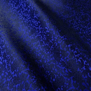 Peut inclure: Gros plan sur un tissu bleu foncé avec un motif floral. Le tissu a un aspect texturé avec un motif bleu plus foncé superposé à un fond bleu plus clair. Le motif est uniforme sur le tissu.