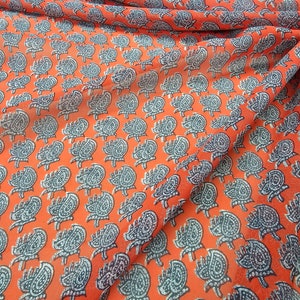 Puede incluir: Tela naranja con un patrón repetido de diseños paisley negros y blancos.