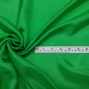 May include: A bright green fabric swatch with a measuring tape laid across it. The tape measures 8 inches.