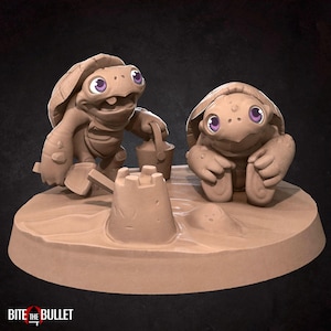 May include: A light brown sculpture of two cartoon turtles constructing a sandcastle. One turtle holds a bucket and shovel, while the other sits close by. The turtles have purple eyes and are on a sandy base. The text "BITE THE BULLET" is at the bottom.