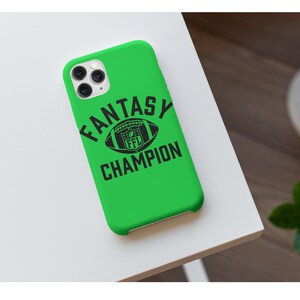 May include: A green iPhone case with a black football and the text "Fantasy Champion" printed on it.