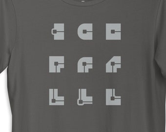 May include: A charcoal grey t-shirt with a graphic design of nine geometric shapes in a light grey color. The shapes are arranged in three rows of three. The text "chris cote" is printed on the tag.