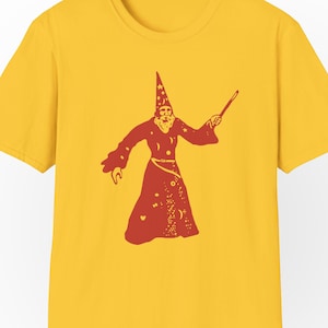 May include: A yellow t-shirt with a red illustration of a wizard wearing a pointed hat and holding a wand. The wizard's robe is covered in stars and other celestial patterns.