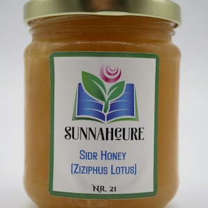 May include: A glass jar filled with golden-colored honey, topped with a gold lid. The jar has a label with the text "SUNNAHCURE" and "SIDR HONEY (ZIZIPHUS LOTUS)". The label also features a logo with a rose and leaves.