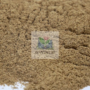 Può includere: Primo piano di un mucchio di polvere fine, marrone chiaro. La polvere ha un aspetto strutturato, con piccoli granuli visibili. L'immagine include un logo con la scritta "SUNNAHCURE".