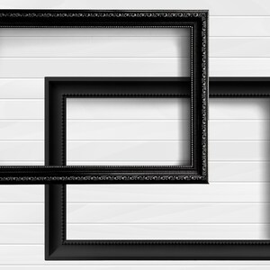May include: Two black picture frames, one slightly larger than the other, are positioned on a white wood panel wall. The frames are both ornate with a decorative border.