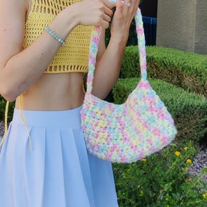 Puede incluir: Un bolso de crochet de color pastel con un top de crochet amarillo. El bolso tiene una correa larga y est&aacute; hecho con una variedad de colores, incluyendo rosa, azul y amarillo.