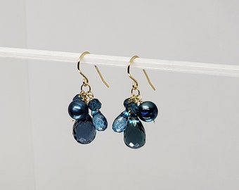 May include: Gold dangle earrings with a cluster of blue topaz and blue pearl gemstones.