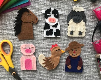 May include: Handmade felt farm animal finger puppets, including a brown horse, a black and white cow, a sheep, a pink pig, a brown chicken, and a farmer. Colorful felt sheets and craft supplies are in the background.