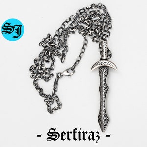 May include: A silver chain necklace with a detailed silver sword pendant. The pendant has an ornate design and a pointed tip. The chain is a simple curb chain.