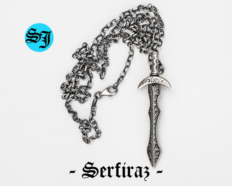 May include: A silver chain necklace with a detailed silver sword pendant. The pendant has an ornate design and a pointed tip. The chain is a simple curb chain.