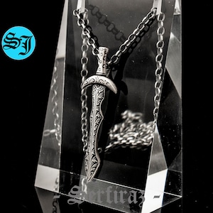 May include: A silver sword pendant necklace with an intricate design. The pendant is hanging from a silver chain.