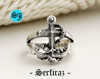 Könnte beinhalten: Ein silberner Ring mit Anker- und Kreuzdesign. Der Anker ist detailliert mit einer Kette umwickelt.