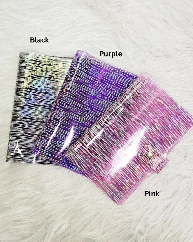 May include: Three clear, glittery pouches in black, purple, and pink. Each pouch has a textured, linear pattern and a snap closure. The colors are labeled on the image.