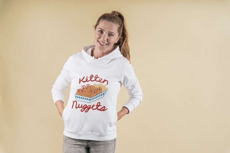 May include: White hoodie with a red and blue graphic of kittens in a box with the text "Kitten Nuggets".