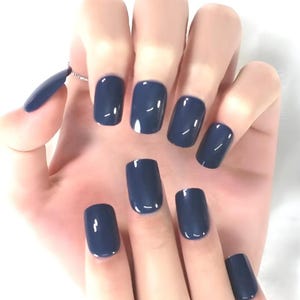 May include: A hand displaying a set of navy blue, square-shaped artificial nails. The nails have a glossy finish and are a solid, dark blue color. The nails are neatly applied and well-manicured.